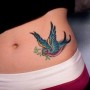 Tatuaggio rondine colorata con rametto